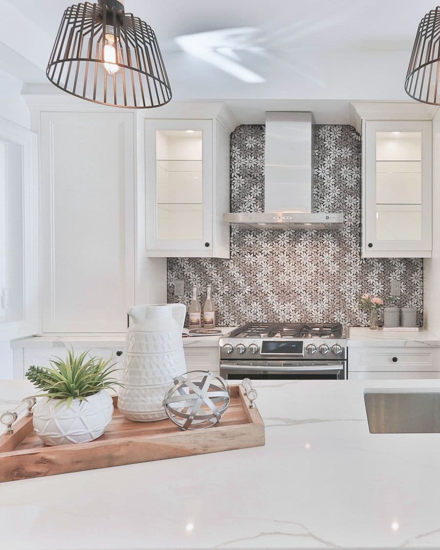 A bright kitchen with a marble island and a white pitcher on a wooden tray.